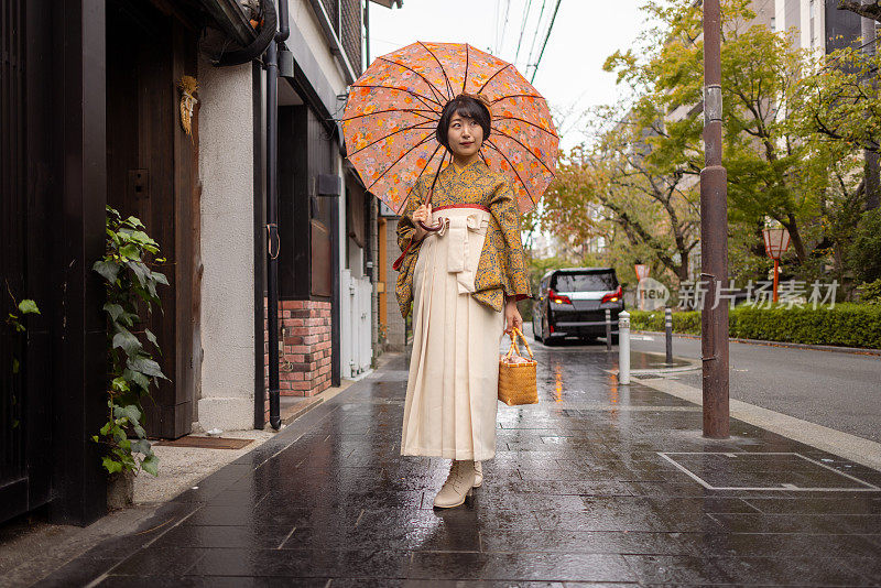 穿着和服/袴的年轻女子在下雨天走在城里的肖像